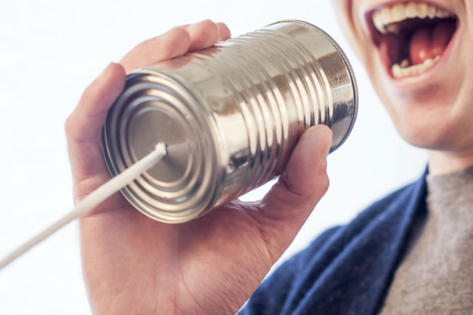 Imagen de un hombre hablando en un teléfono hecho con lata y cordel